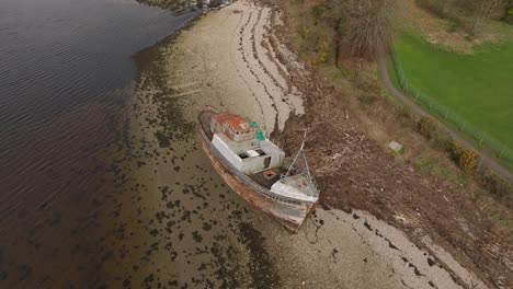 Aerial-orbiting-shot-of-the-Corpach-Shipwreck-angled-on-the-shore-of-Fort-William