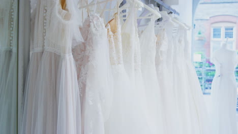 close up of beautiful bridal wedding dresses hanging on rail in shop