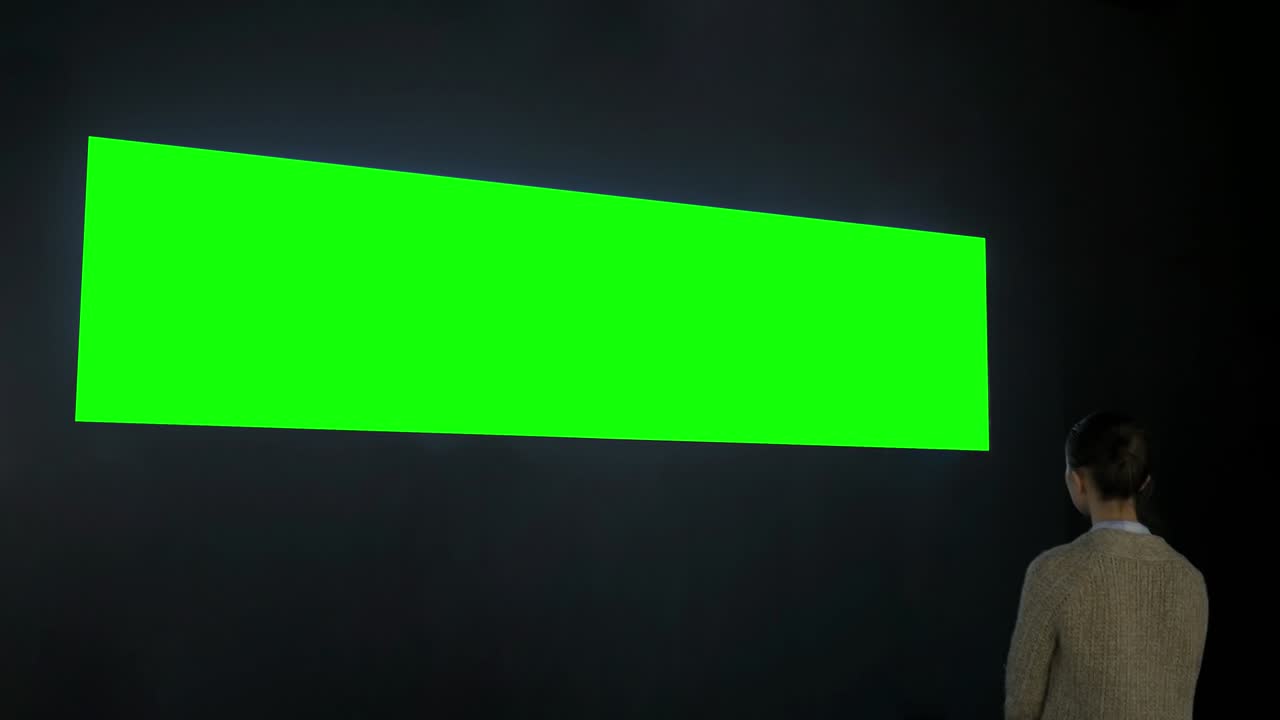 donna che guarda un ampio display interattivo a parete vuoto - concetto di schermo verde