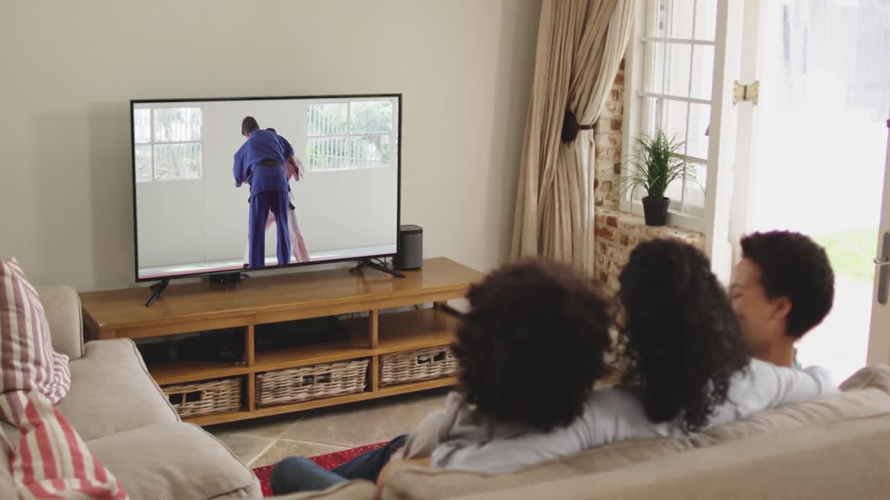 Famiglia felice seduta a casa insieme che guarda un incontro di judo in TV