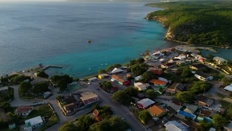 Aerial-establishing-overview-of-Boka-Sami-beach-with-boats-docked-on-sandy-ocean-water-at-sunset