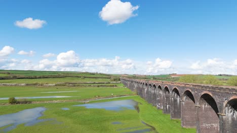 drone flight alongside historic welland viaduct northamptonshire, otherwise know as the harringworth and seaton viaduct on sunny day showing whole expanse of england’s longest viaduct and valley below