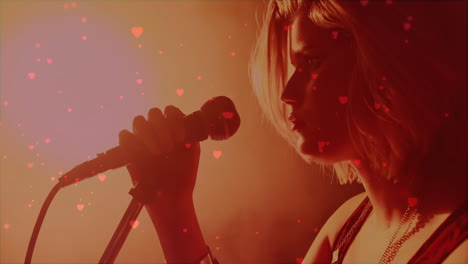 teenage female singer performing in music industry scene with floating heart icons and red lighting