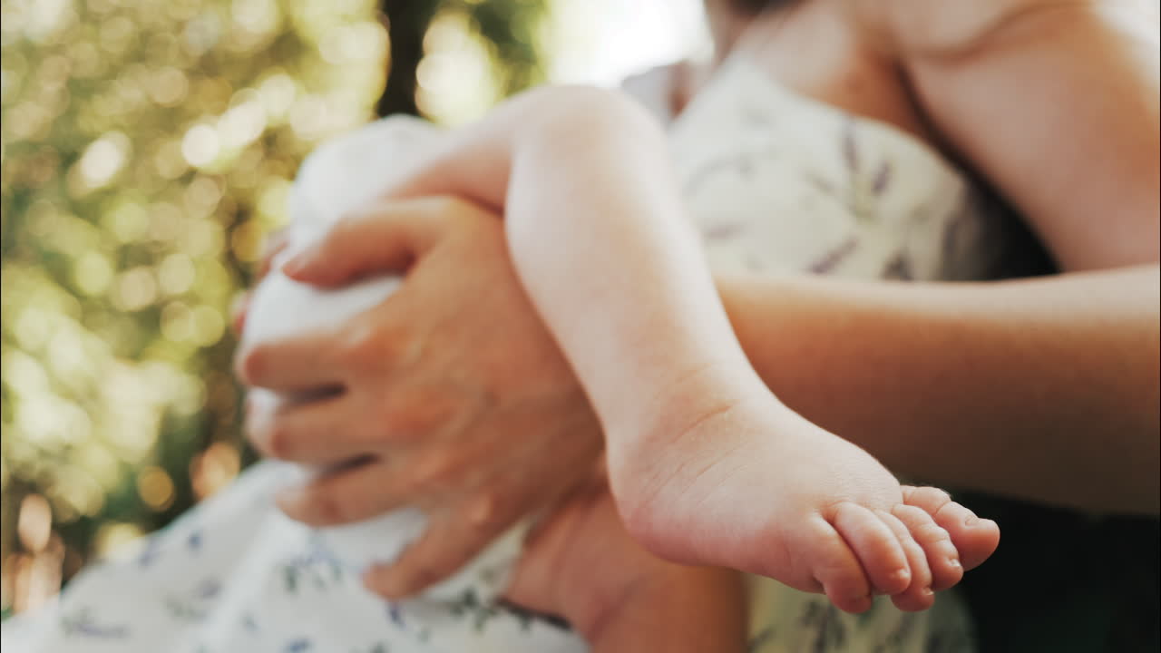 Tender moment of a mother breastfeeding her baby on a green park bench in daylight