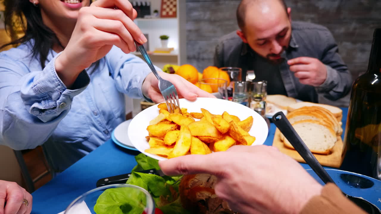 Plano sequência de um jovem servindo batatas à sua irmã.