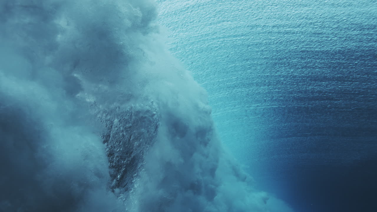 Breaking underwater wave with textured surface and turquoise light near the face