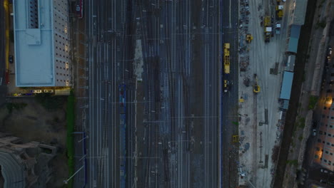 Birds-eye-shot-of-train-driving-on-railway-in-city-in-evening.-Tracking-of-electric-locomotive-with-passenger-cars.-Rome,-Italy