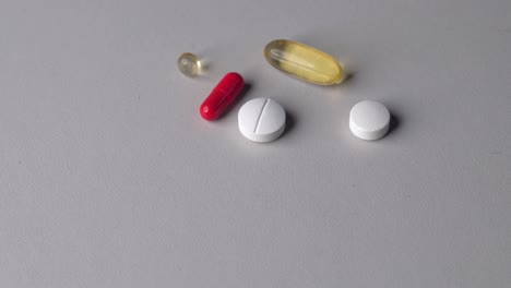 person put multiple colorful vitamin pills and capsules on table surface