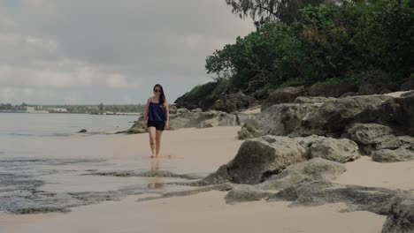 Front-view-of-girl-walking-on-the-beach-during-a-sunny-and-bright-morning