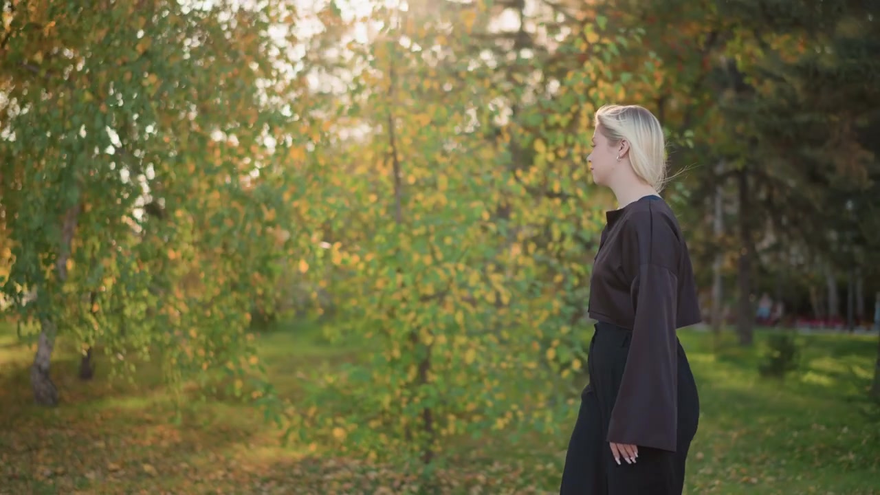 Giovane donna che cammina in un parco durante l'autunno.