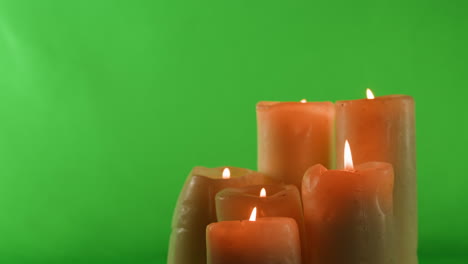 four lit candles on green screen