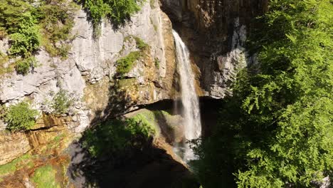 berglistüber waterfall cascading from rocky cliff into lush green canyon in switzerland