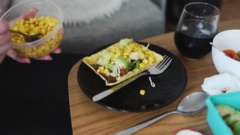 poner un poco de maíz en la carne de soya picada vegana sobre una tortilla de cáscara dura