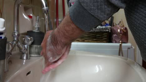 man in quarantine washing his hands in a sink