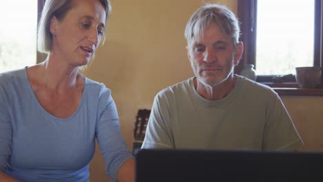 Pareja-Caucásica-Mayor-Usando-Una-Computadora-Portátil-Y-Sentada-En-La-Mesa