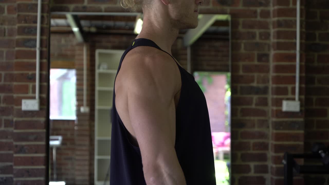 아령 어깨 측면 인상을 하 고 홈 체육관에서 문신 남자 근육