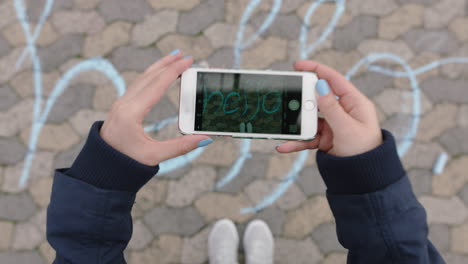 Frau-Von-Oben-Mit-Smartphone-Fotografiert-Kreideschrift-Auf-Dem-Spielplatz-Und-Teilt-Nette-Nachrichten-In-Den-Sozialen-Medien