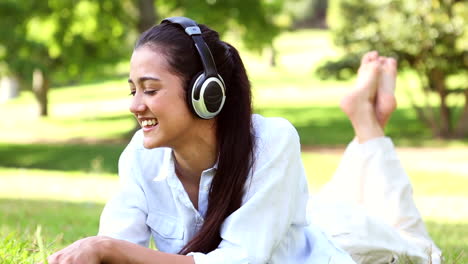 pretty girl lying on the grass listening to music