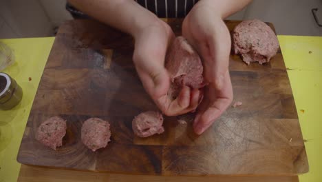 Cierra-Las-Manos-Del-Chef-Formando-Albóndigas-Y-Colócalas-Encima-De-Una-Tabla-Cortada-De-Madera