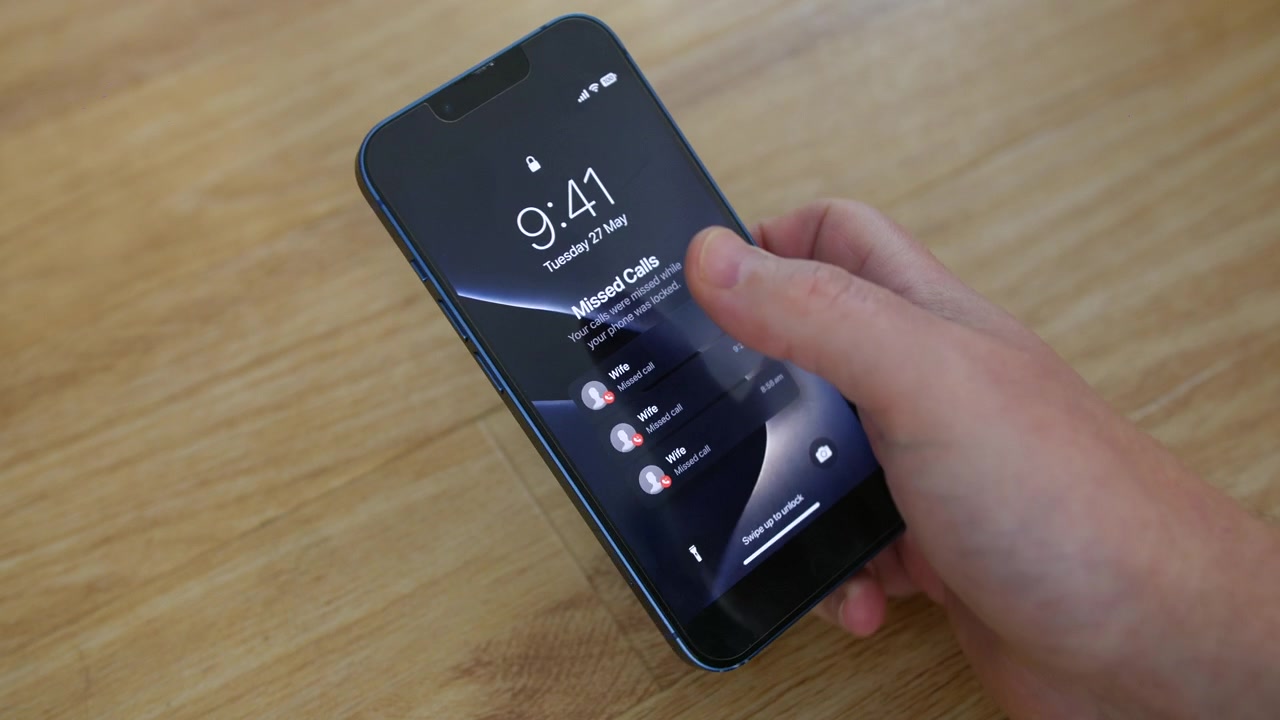 Telefone mostrando chamadas perdidas da Esposa repousa sobre uma mesa de madeira enquanto uma mão toca a tela de bloqueio. Vista em close-up de celular, smartphone destaca alertas de contato de cônjuge, parceiro, família