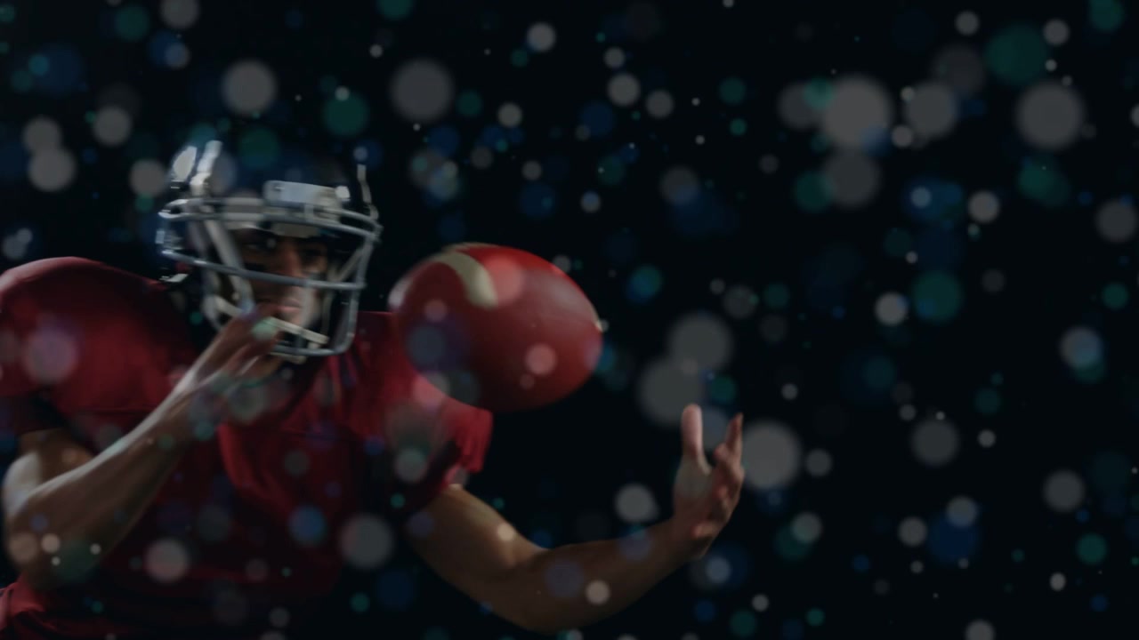 Un giocatore con casco che afferra il pallone da football americano entrando nell'inquadratura, stringendo a sé e proteggendo il pallone in un bokeh sportivo.