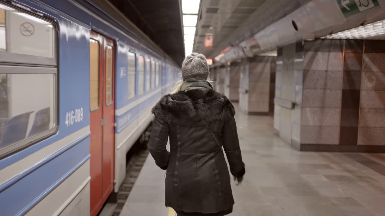 Woman walks along a train platform in a subway station