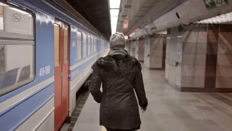 woman walks along a train platform in a subway station