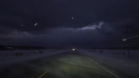 pov shot of a car driving through road with winter blizzard and roadside snow at night, ontario, canada