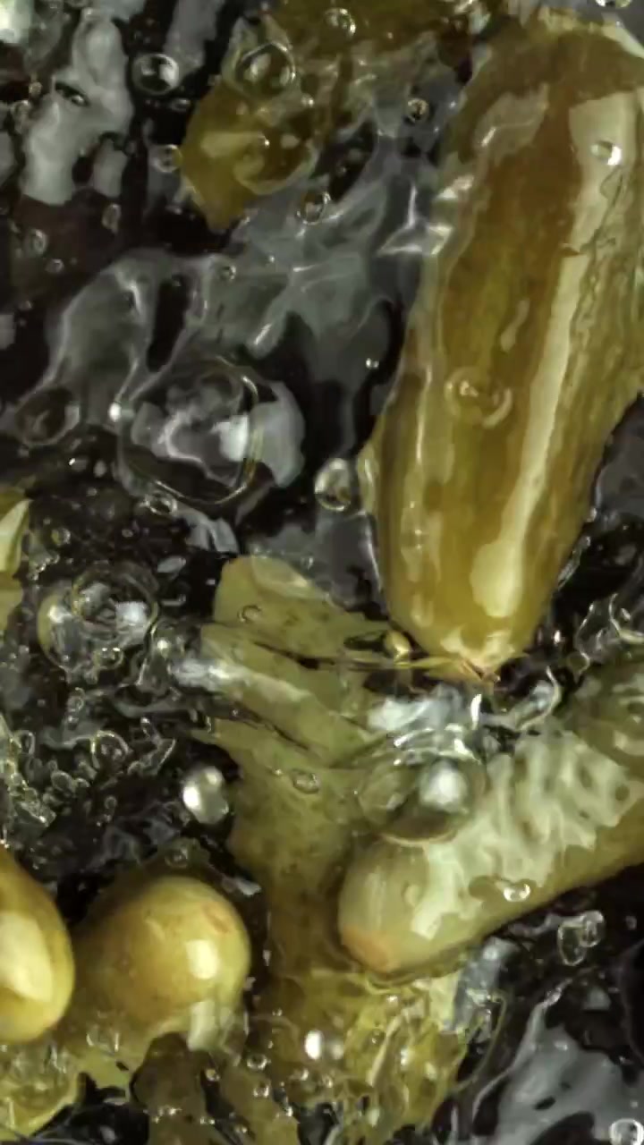 Syltede agurker falder ned i vand i slow motion