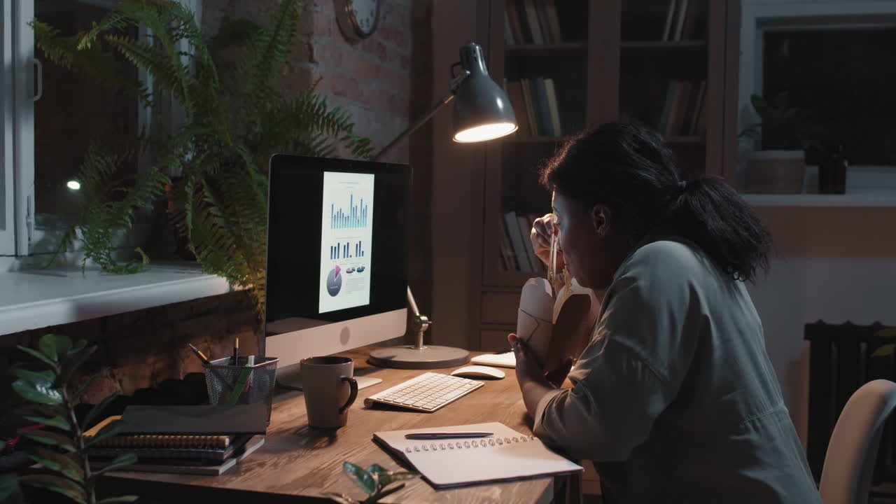 Persona che lavora fino a tardi di notte al computer e mangia cibo da asporto