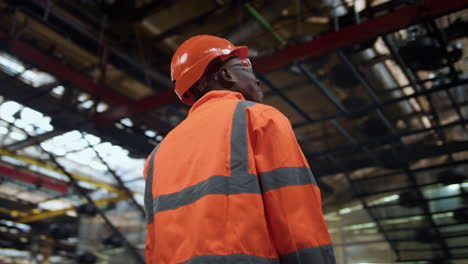 supervisor alegre mirando la cámara en el moderno almacén de instalaciones industriales enormes.