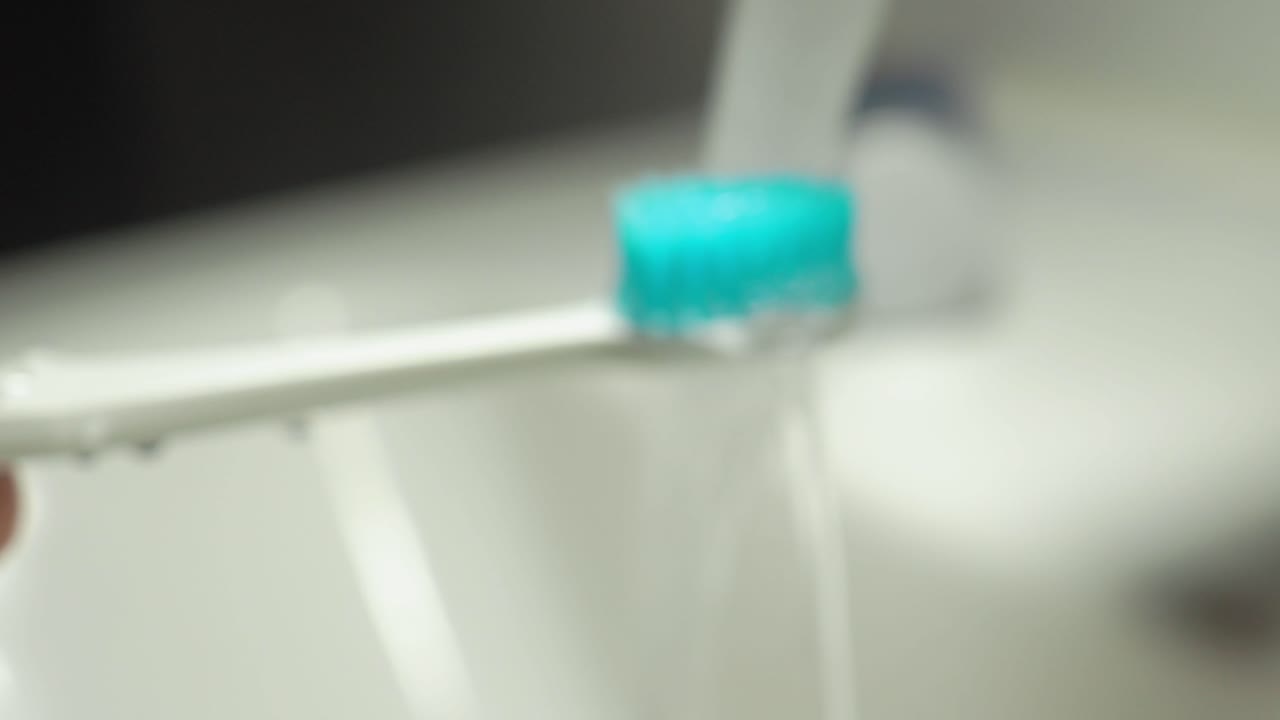 Electric toothbrush being rinsed under running water