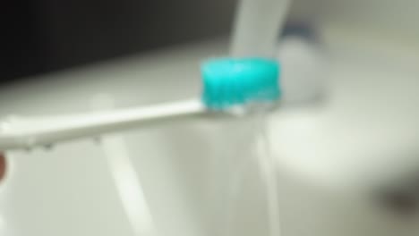 electric toothbrush being rinsed under running water