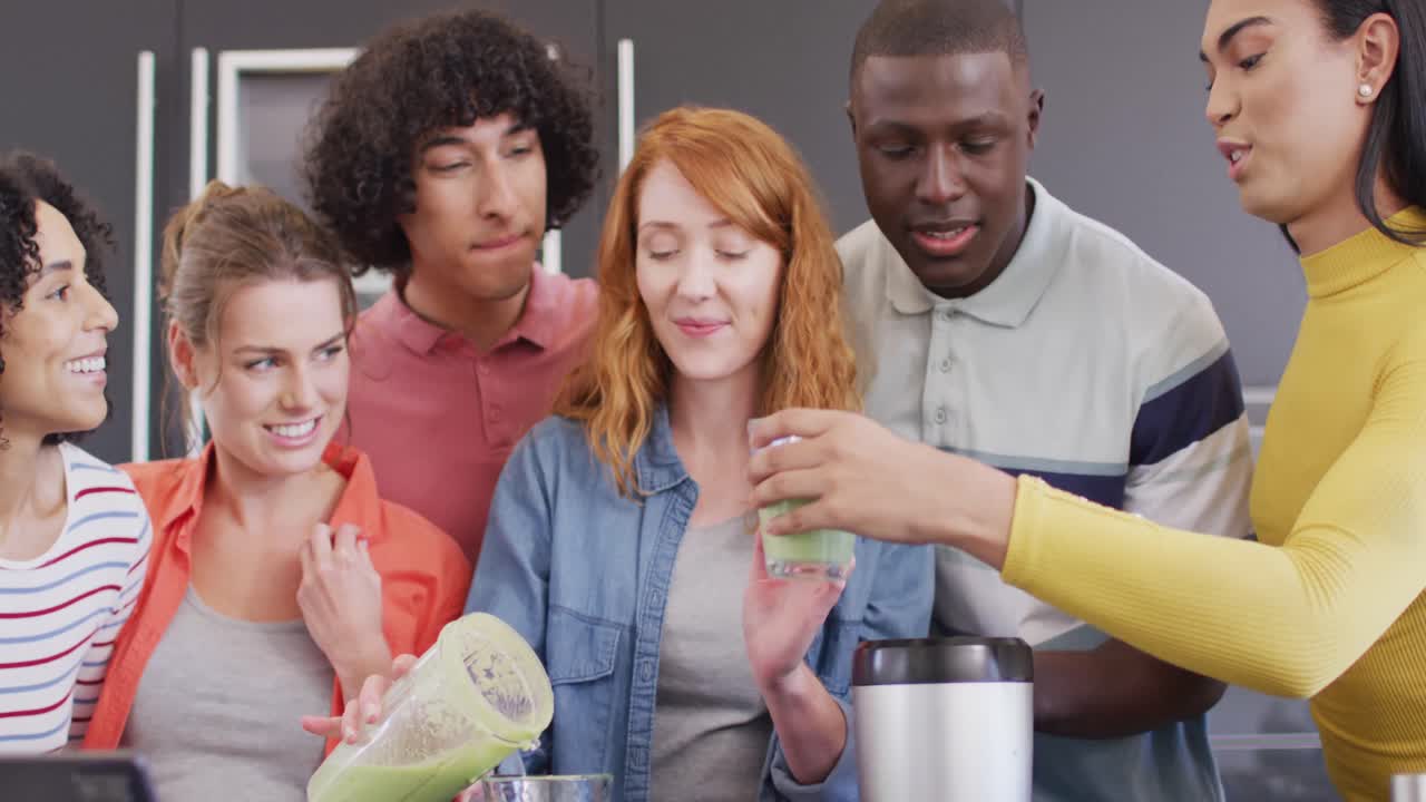 un grupo feliz de amigos diversos preparando una bebida saludable en la cocina juntos