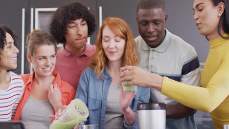 happy group of diverse friends preparing healthy drink in kitchen together