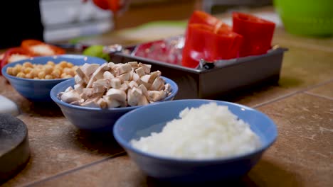 mirada colorida a la cebolla picada, los champiñones, los garbanzos y otros ingredientes para una receta casera de pimientos rellenos