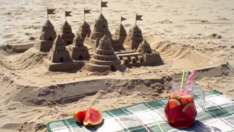 an enchanting beach scene featuring intricate sandcastles surrounded by refreshing drinks and vibrant fruit, perfect for a summer day celebration