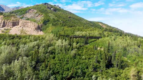 Video-De-Drones-De-4k-Del-Puente-De-Caballetes-Del-Tren-Y-Montañas-Que-Se-Elevan-Sobre-El-Río-Chulitna-Cerca-Del-Parque-Nacional-Y-Reserva-Denali,-Ak-Durante-El-Verano