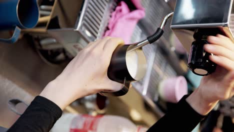 vertical, coffee mug is held up against silver machine to stir fill and brew