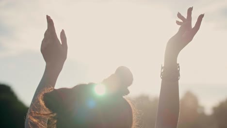 Rear-view-of-woman-with-hands-raised-dancing-outdoors