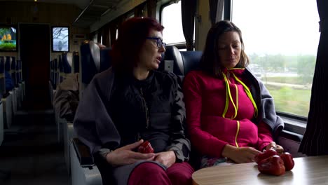 women go on the train, talk and eat fruit