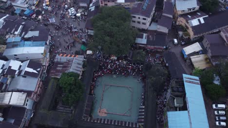 Aerial-of-the-crowd-of-Hindu-devotees-approaching-Kushavarta-Kund-to-take-holy-dip-early-morning-during-the-month-of-Shravana,-Sacred-bathing-pond-near-Trimbakeshwar-temple,-Nashik,-Maharashtra,-India