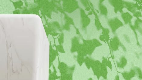 white marble pedestal with shadow of branches on a green background