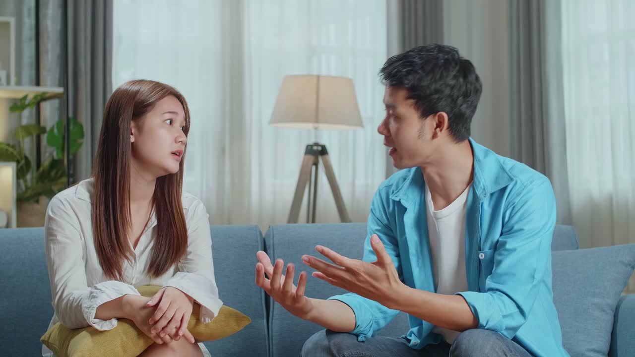 Angry Young Asian Couple Sit On Couch In Living Room Having Family Fight Or Quarrel Suffer From Misunderstanding, Millennial Husband And Wife Dispute Involved In Argument, Relationships Problems Concept