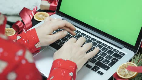 portátil con pantalla verde en la mesa. espacio de copia de pantalla chromakey. manos de persona que trabaja en una computadora portátil con screen verde, escribiendo mensajes, desplazando noticias en las redes sociales, haciendo compras en línea