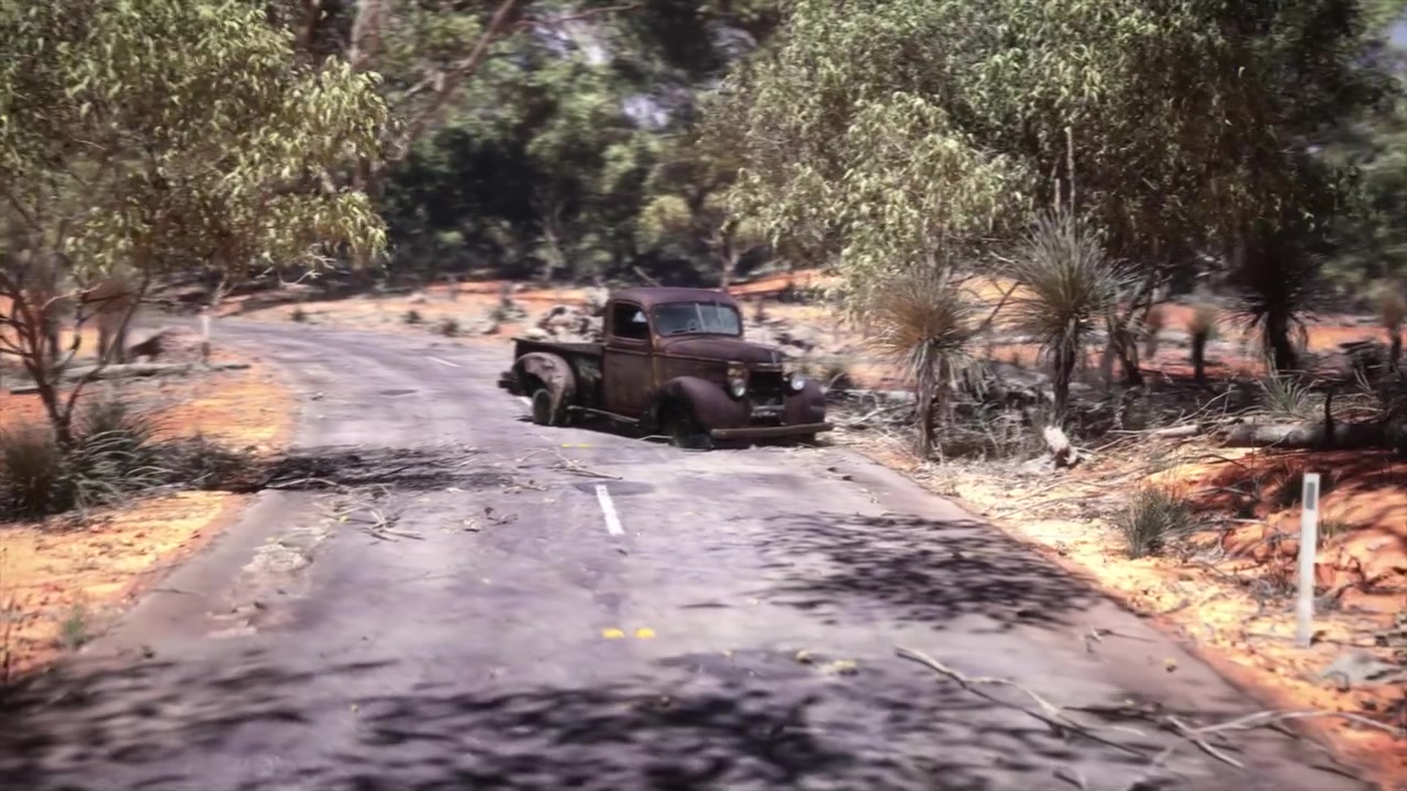 Wild and unforgiving bushland in remote outback Australia with its tough vegetation and red earth, this abandoned country road has a long-forgetten and rusted old car wreck blocking the road