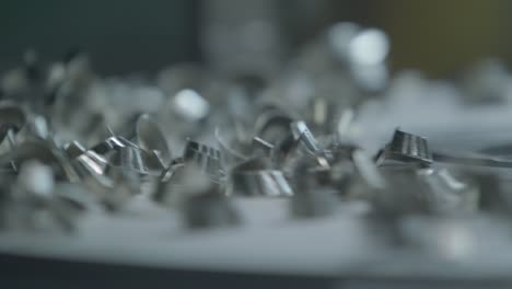 macro close-up of metal fragments circling on a steel sheet as it is being carved by a milling machine