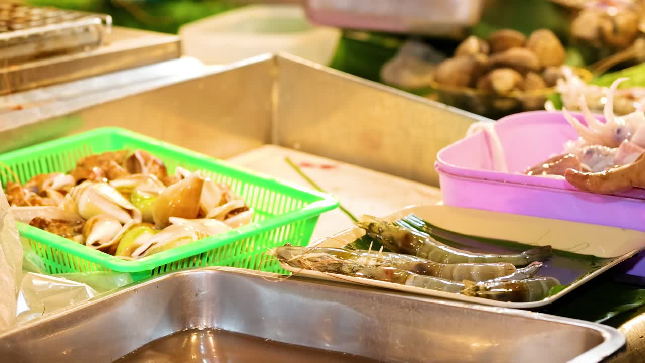Hands sorting seafood into trays at a vibrant market stall, showcasing fresh ingredients and local trade.