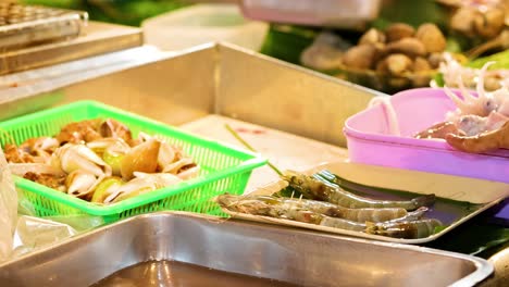 hands sorting seafood into trays at a vibrant market stall, showcasing fresh ingredients and local trade.