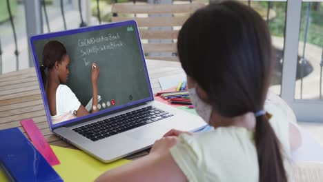 Kaukasisches-Schulmädchen-Mit-Gesichtsmaske,-Das-Einen-Laptop-Bei-Einem-Videoanruf-Mit-Einer-Lehrerin-Benutzt